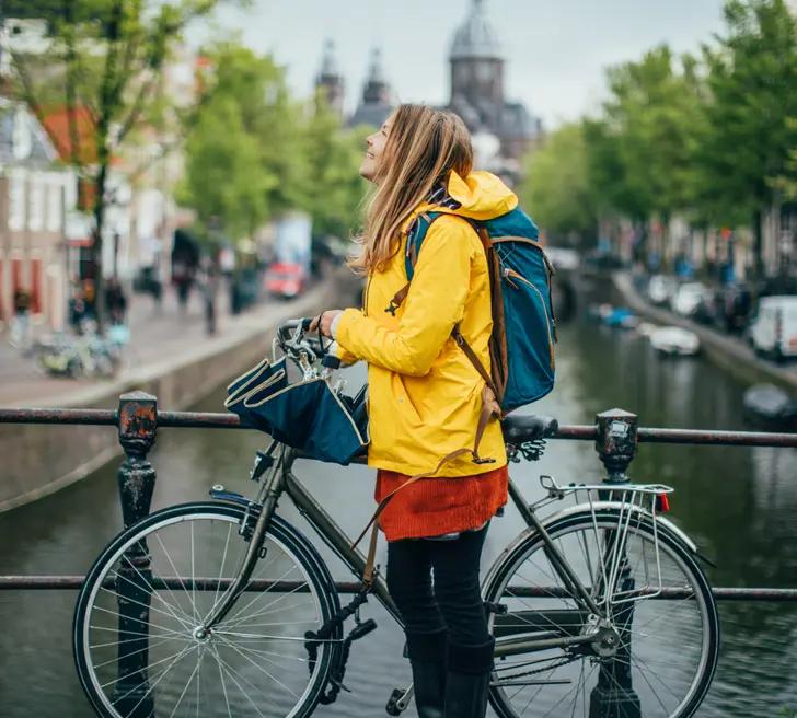 Vrouw staat met fiets op brug in Amsterdam