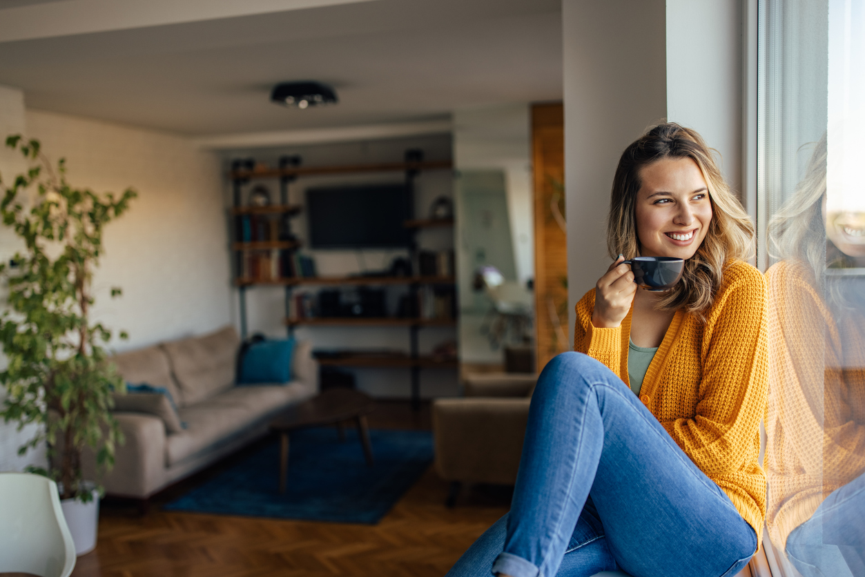 vrouw drinkt thuis koffie tegen raam